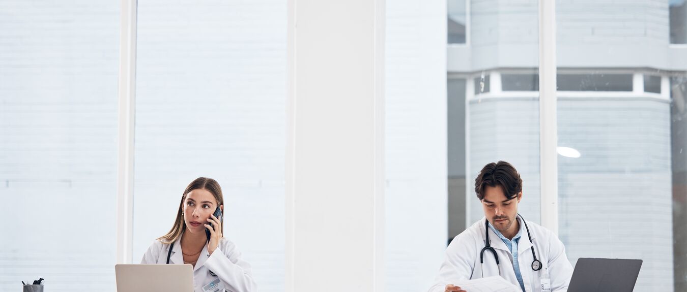 Doctors, team and hospital phone call, planning or communication for telehealth services or clinic research. Medical people working in office or reception desk with laptop, documents and mobile chat